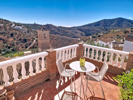 Roof terrace with table and seats of Cortijo Fuente Perdida in Daimalos with the view over the hills of the Axarquia