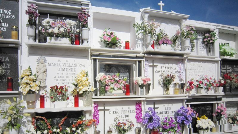 Eine Zeile von Gräbern auf einem spanischen Friedhof geschmückt mit Blumen